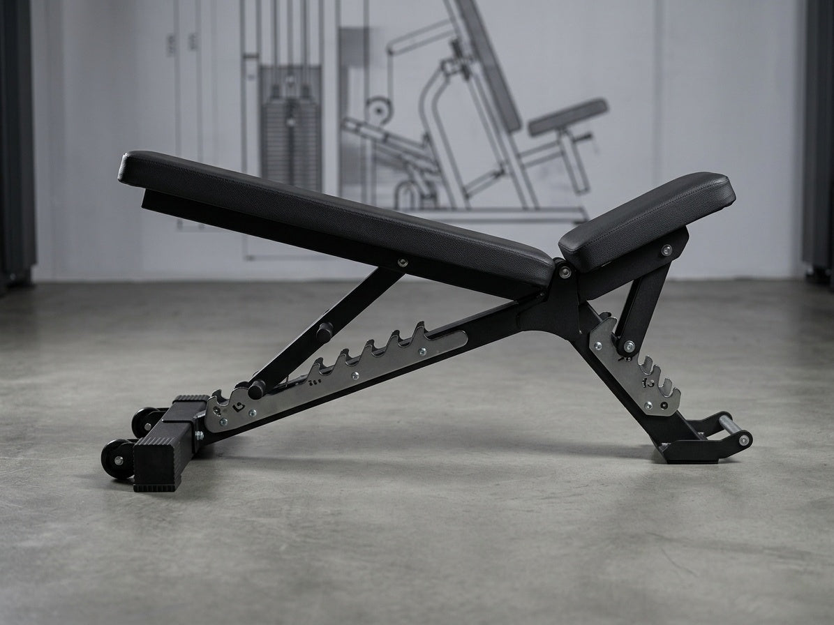 A black adjustable weight bench with a metal frame and leg rests, positioned on a concrete floor in a gym setting.