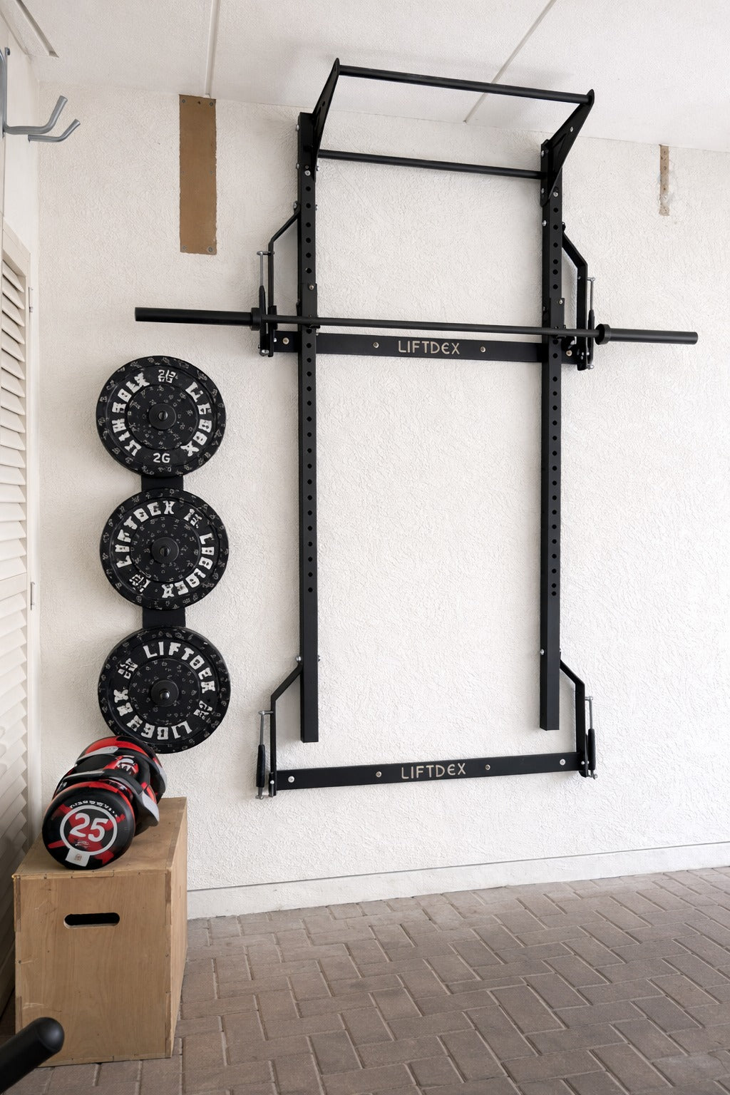 Wall-mounted pull-up bar with weight plates and a box in a home gym setting.