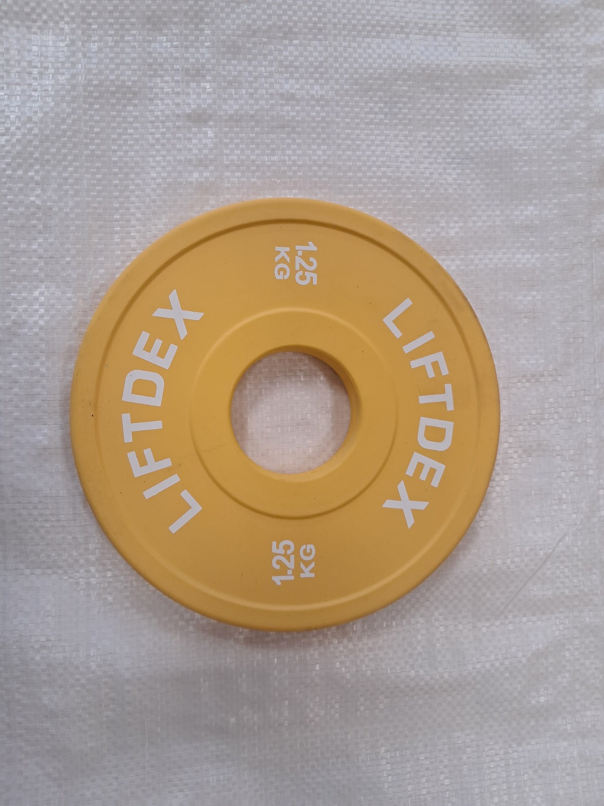 Yellow weight plate with 'LIFTDEX' branding on a light yellow plate